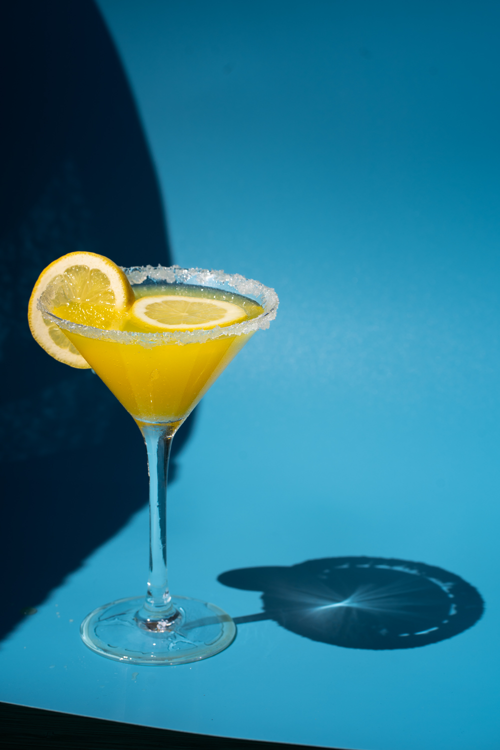 Gelber-Cocktail-Drink-Zitrone-blauer-Hintergrund-Sommer-Hardlight